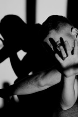Man in dramatic lighting covering his face with hand to partly hide his face