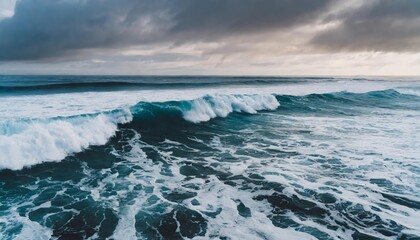 Fototapeta premium Foamy waves rolling gently across a serene ocean landscape at sunset, capturing natures raw beauty with white surf meeting deep blue waters under an endless horizon.