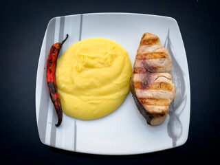 Grilled fish served with mashed potatoes and a roasted pepper