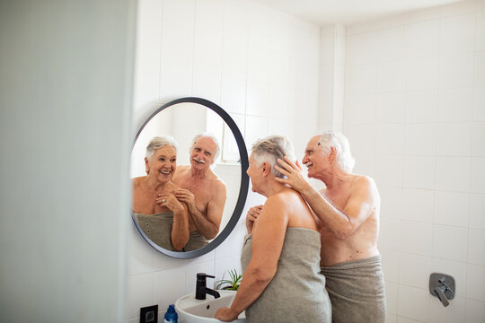 Elderly couple sharing a playful moment in front of the bathroom mirror