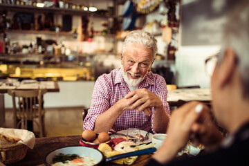 Senior couple eating food in cozy restaurant bistro