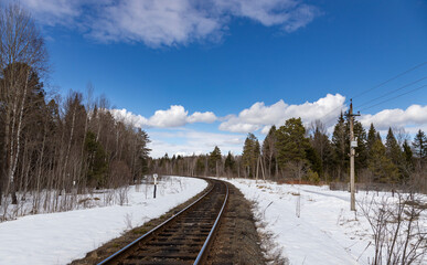 Train track is shown in the snow with a blue sky in the background