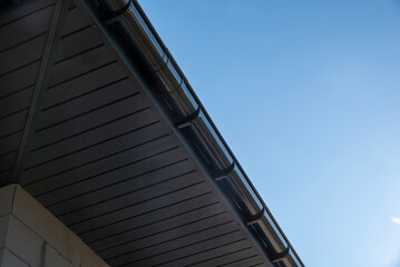 Metal soffit and gutter installation highlighting sleek design against a clear blue sky