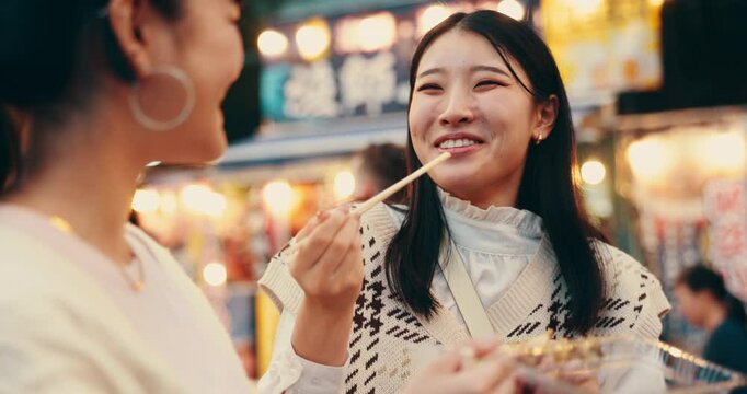 Friends, food and eating for street market, bonding and conversation with celebration in Japan at night together. Women, talking and laughing in Tokyo for culture, festival and community with travel