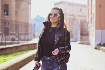 Rome,Italy, Young beautiful woman  near The Fori Imperiali enjoying the city at Rome during language vacation. Using a mobile phone taking a pictures.Concept of Italian gastronomy and travel