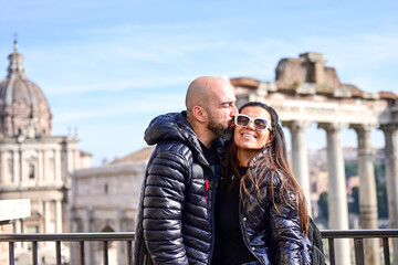 Fototapeta premium Happy Beautiful Tourists couple traveling at Rome, Italy, near Ancient Trajan's Market, ruins in Via dei Fori Imperial Visiting Italy - man and woman enjoying weekend weekend vacation - 