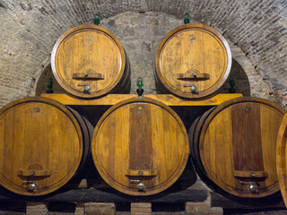 Wooden barrels are stored in an old wine cellar