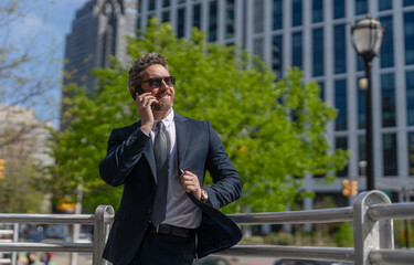 Business communication. Business man having phone call outdoor. Businessman using phone. Communication channels. Man phone conversation in suit. Middle aged Hispanic businessman with phone