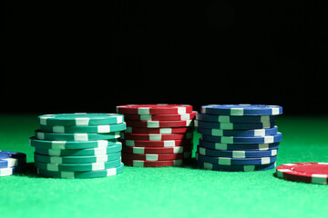 Poker chips on green table against dark background, closeup