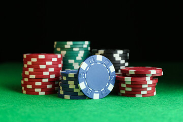 Poker chips on green table against dark background, closeup