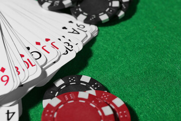 Playing cards and poker chips on green table, closeup. Space for text