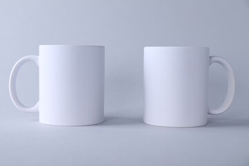 Two blank white mugs on light background. Mockup for design