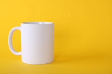 One blank white mug on yellow background. Mockup for design