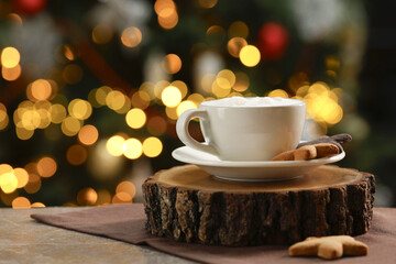 Aromatic coffee in cup and tasty cookies on table against blurred Christmas lights, space for text. Bokeh effect