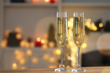 Champagne in glasses on wooden table against blurred Christmas lights, space for text. Bokeh effect