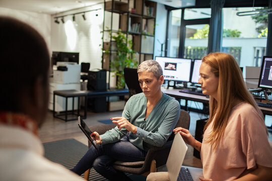 Team collaboration in modern office space with diverse professionals using laptops and discussing project