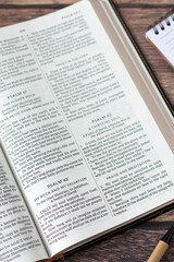 Open holy bible book with notebook and pen on wooden desk. God is my Rock and salvation. Studying and reading old testament Scripture. Christian biblical concept.