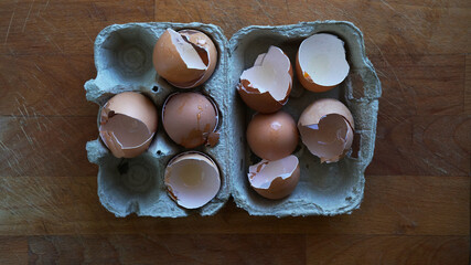 broken and empty eggs inside recycled cardboard container, top view