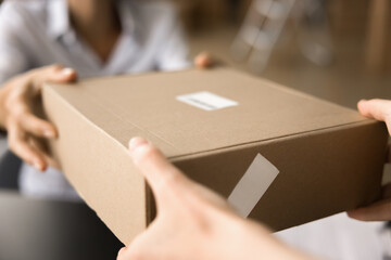 Female hands of transportation manager, courier, giving cardboard paper box to customer. Client...