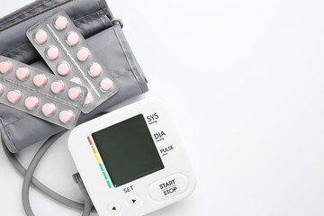 Blood pressure measuring device and pills on white background, top view. Space for text