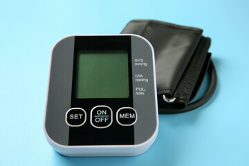Blood pressure measuring device on light blue background, closeup