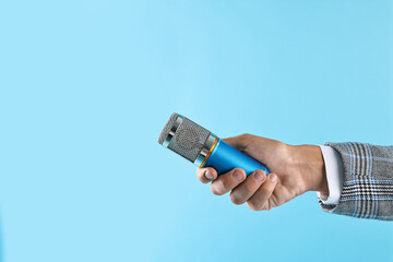 Man with microphone on light blue background, closeup