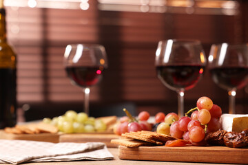Glasses of red wine and different snacks on wooden table, selective focus. Space for text
