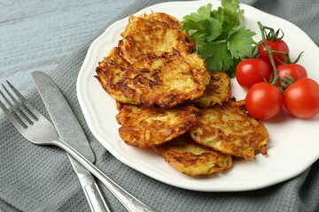 Delicious potato pancakes with tomatoes and parsley served on gray wooden table, closeup