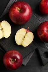 Whole and cut ripe red apples on black wooden table, flat lay