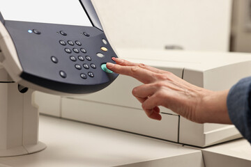 Woman using modern printer indoors, closeup. Printing house