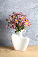Stylish vase with beautiful flowers on wooden table
