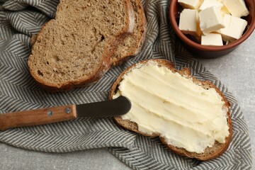 Fresh bread with butter and knife on grey table, flat lay