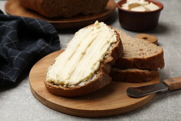 Fresh bread with butter and knife on grey table, closeup