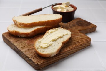 Fresh bread with butter on white tiled table, closeup