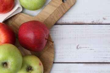 Different whole ripe apples on white wooden table, flat lay. Space for text