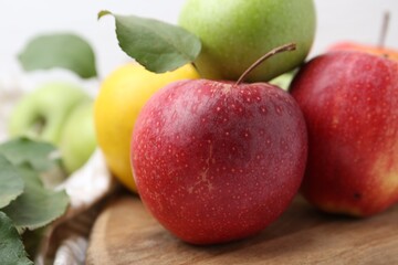 Different whole ripe apples on wooden table, closeup