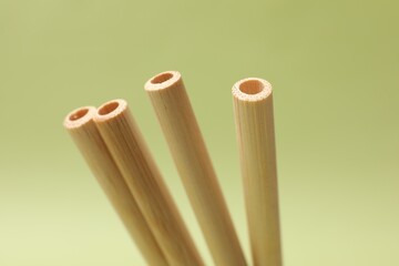 Bamboo drinking straws on light green background, closeup
