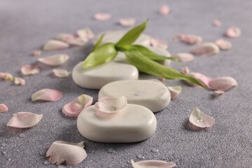 Fototapeta premium Spa stones, petals and green leaves on grey table, closeup