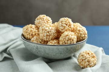 Tasty puffed rice balls in bowl on table, closeup