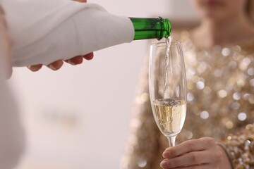 Waiter pouring champagne into woman's glass, closeup