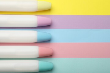 Sticks of glue on color background, flat lay. Space for text