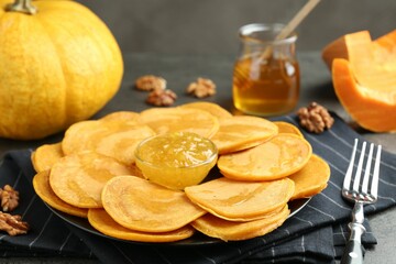 Tasty pumpkin pancakes with honey, walnuts and jam on table, closeup
