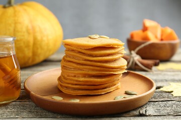 Tasty pumpkin pancakes with seeds served on wooden table, closeup