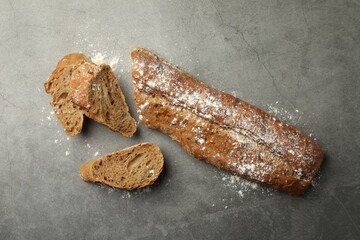 Cut fresh baguette on grey table, flat lay