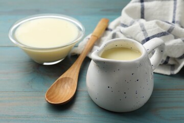 Condensed milk and spoon on light blue wooden table, closeup