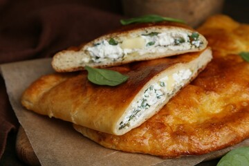 Tasty calzones with cheese and basil on table, closeup