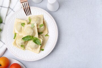Delicious ravioli with cheese and basil served on light table, flat lay. Space for text