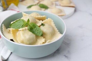 Delicious ravioli with cheese and basil served on white marble table, closeup
