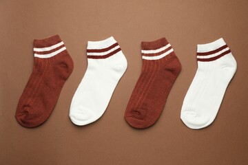 Different soft socks on light brown background, flat lay