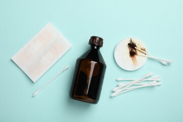 Topical iodine and other first aid kit components on light blue background, flat lay